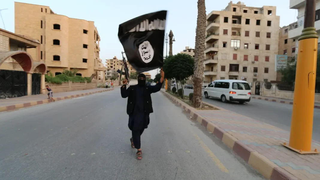 A member loyal to the Islamic State in Iraq and the Levant waves an ISIS flag in Raqqa on June 29, 2014.
