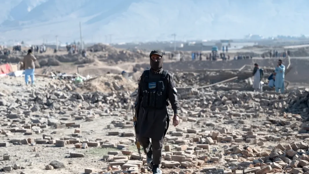 A Taliban security officer walks past rubble at the site of a Pakistani airstrike on the outskirts of Kabul on March 13